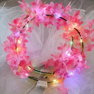 Detail of pink floral LED headband featuring glowing lights and white battery box