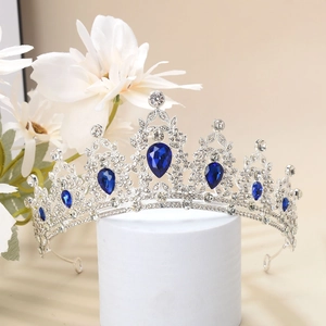 Detailed close-up of a royal crown with teardrop blue gems and clear rhinestones