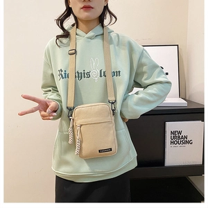 Detailed close-up of a mini canvas crossbody bag worn by a model in a modern interior
