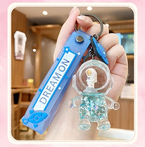 Detailed view of astronaut keychain featuring blue silicone strap and liquid glitter bottle