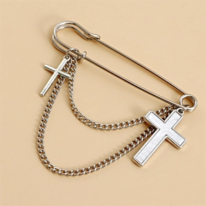 Close-up of silver metal brooch with crystal evil eye and dangling cross chains detail