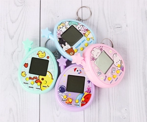 Flat lay of colorful egg-shaped virtual pet game machines with keychains on wooden background
