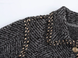 Detail of dark grey tweed jacket featuring gold embossed buttons and woven braid trim