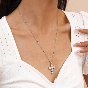 Detail of silver cross pendant with pearls worn over elegant white lace clothing