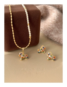 Detailed set of gold plated pony jewelry with pearls and colorful gems on a brown gift box