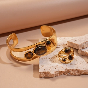 Nahaufnahme des 18k vergoldeten Manschetten- und Ringsets mit ovalen Tigerauge-Steinen
