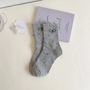 Close-up of grey polka dot socks featuring black bow details and ruffled lace elastic cuffs