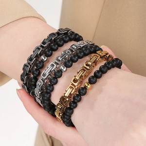 Close-up of stacked Byzantine chains and matte black onyx beads on a male model's wrist
