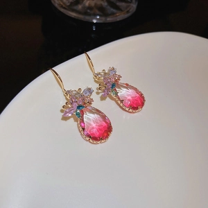 Détail de boucles d'oreilles en goutte avec dégradé rouge et accents floraux dorés