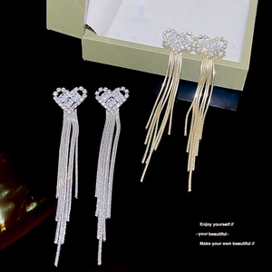 Detail of silver and gold heart earrings with long tassels and sparkling rhinestones