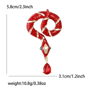 Red enamel snake brooch with gold accents and dangling red teardrop gemstone
