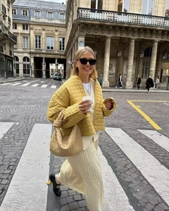 Street style shot of a yellow quilted jacket and beige woven handbag in Paris