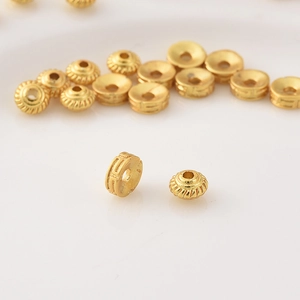 Macro shot of 18K matte gold UFO spacer beads with vintage texture for DIY jewelry