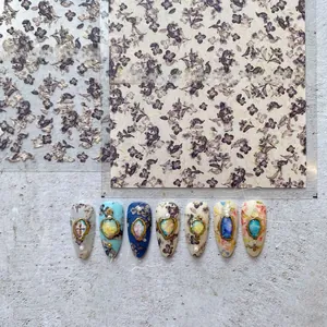 Detailed application of purple floral nail stickers with vintage gold frames and pearls