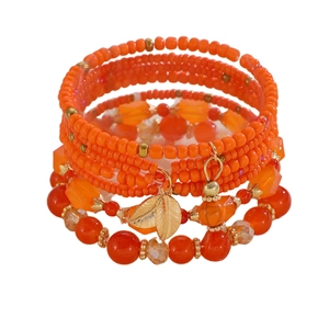 Dettaglio di un bracciale bohémien a più strati con perline arancioni e ciondolo a foglia