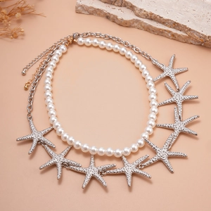 Detail of double-layer necklace with white faux pearls and textured silver starfish pendants