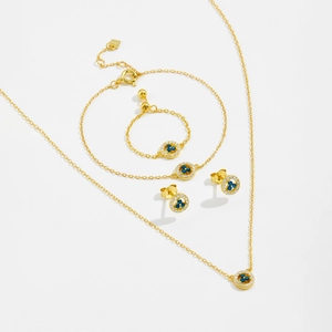 Detailed set of gold jewelry with blue sapphire gems and diamond halo on white background