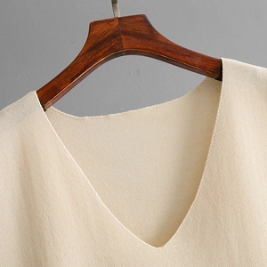 Detail of V-neck stitching and high-density knit texture on a beige sleeveless top