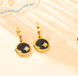 Vue macro de boucles d'oreilles lune et étoile dorées avec émail noir et cristal serti