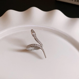 Macro detail of silver snake ring with scale texture on a white ceramic display