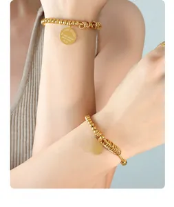Detail of gold beaded bracelet featuring a round pendant engraved with Fantastic New York