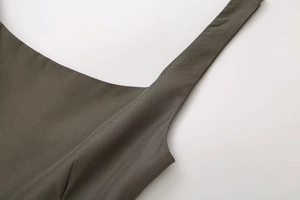 Detailed close-up of olive green pleated dress showing twill fabric texture and stitching