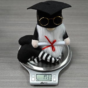 Detail showing graduation gnome doll with black cap, golden glasses and diploma