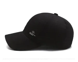 Detailed side view of black baseball cap showing silver metal logo and stitched brim