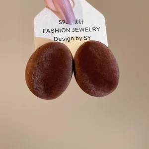 Détail macro des boucles d'oreilles ovales floquées marron avec tiges en argent S925