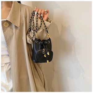 Detail of black leather mini bucket bag featuring quilted pocket and gold chain strap