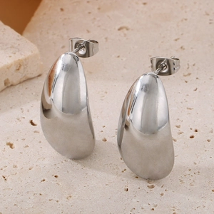Macro shot of silver teardrop stud earrings on stone background highlighting sleek metal finish