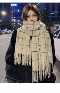 Detailed view of cream and black checkered scarf with soft wool texture and fringe trim