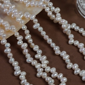 Polished 4-5mm natural freshwater white pearls in a strand on elegant silk fabric