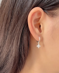 Detailed close-up of a silver four-leaf clover earring with sparkling micro-inlaid stones