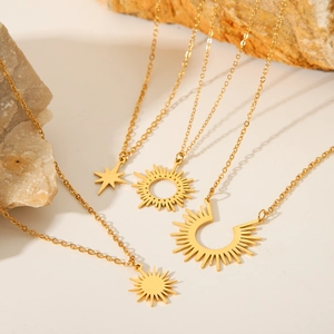 Detail of four 18K gold-plated stainless steel sun and star pendant necklaces on stone