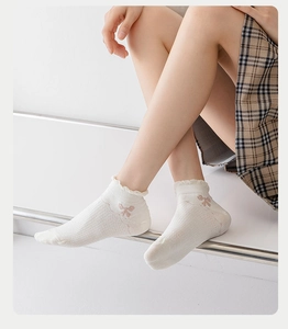 Detail of white mesh summer socks with lace trim and elegant bow patterns on the side