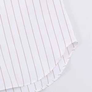 Detail view of a striped poplin shirt featuring a curved hem and fine brown vertical stripes