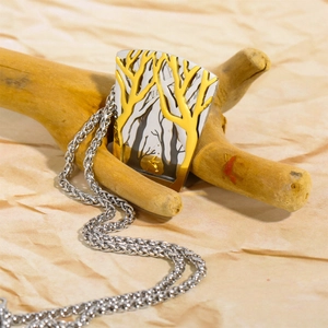 Detail of two-tone gold and silver forest bird pendant on a vintage steel chain