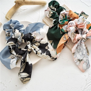 Detailed flat lay of floral satin hair scrunchies with long ribbons in four colors