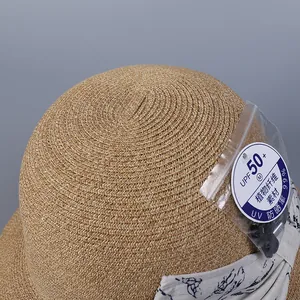 Close-up of straw sun hat with UPF 50+ tag and blue floral ribbon detail