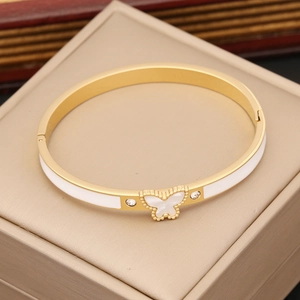 Detail of gold butterfly bangle with white enamel inlay and sparkling side crystals