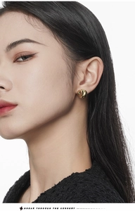 Close-up of irregular textured golden ball earrings worn on model for daily style