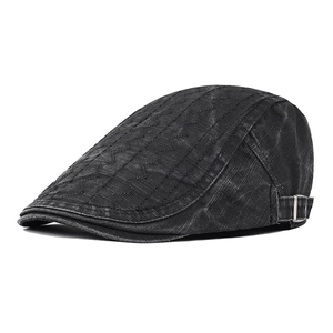 Detail of vintage black denim flat cap with wavy embroidery and silver metal buckle