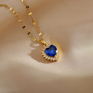 Detail of a heart-shaped blue sapphire pendant with micro-paved white stones on gold chain