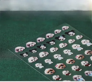 Detail of adhesive nail stickers featuring cute poodle dog patterns on dark green fabric