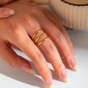 Close-up of three 18K gold-plated stainless steel rings with plain and twisted textures