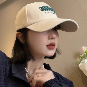 Close-up of beige baseball cap featuring green Hate NEW LIFE letter embroidery on front