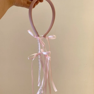 Detailed shot of pink fabric headband featuring satin bows and crystal tassel fringe