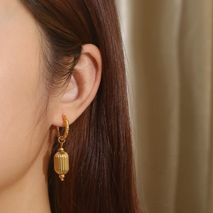French vintage gold C-shaped hoop earrings with spiral texture and capsule pendant on model