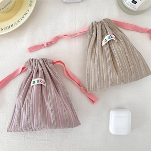 Close-up of striped drawstring storage bags with pink woven cords and fabric brand labels